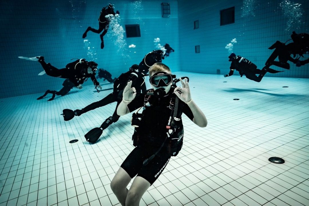 Prova på dyk i pool undervattensfoto med flera dykare
